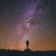 een sterrenhemel in de nacht met een silhouet van een persoon